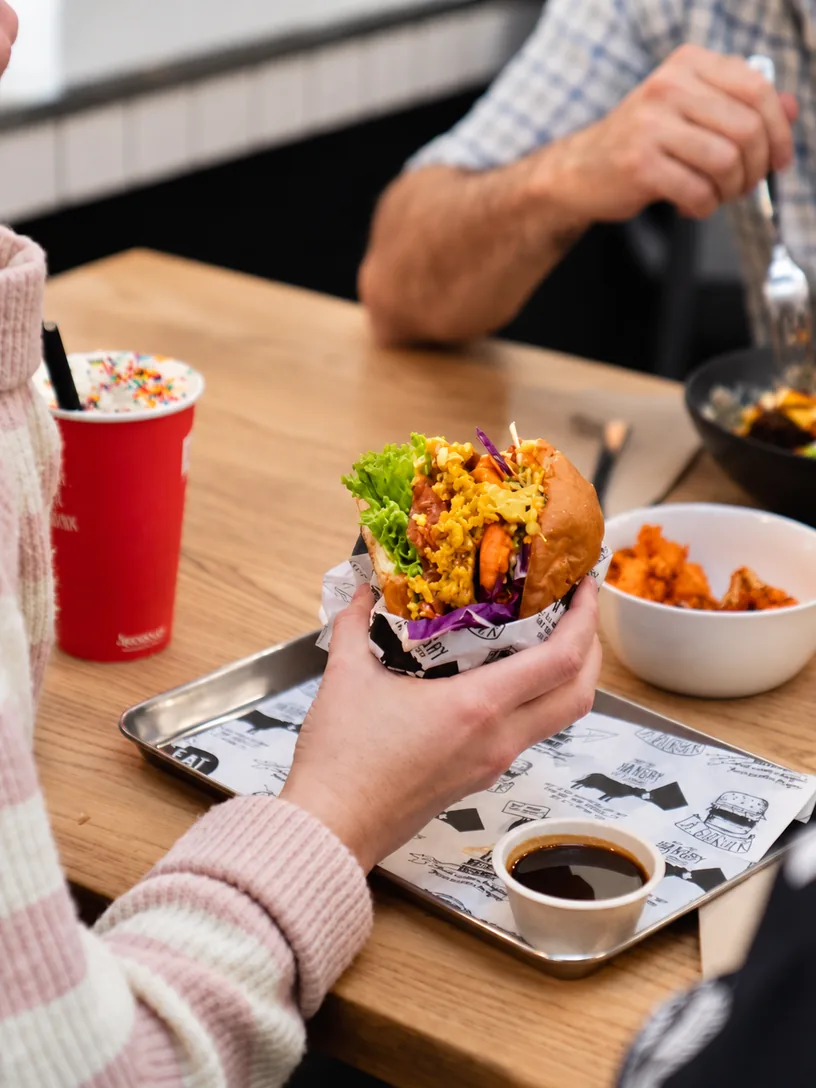 A guest holding a burger at an Eat Burger table